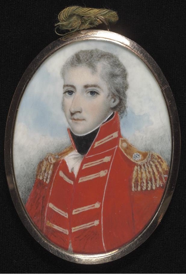 A painted locket portrait of a man in a red military uniform. The locket is resting on some black material.